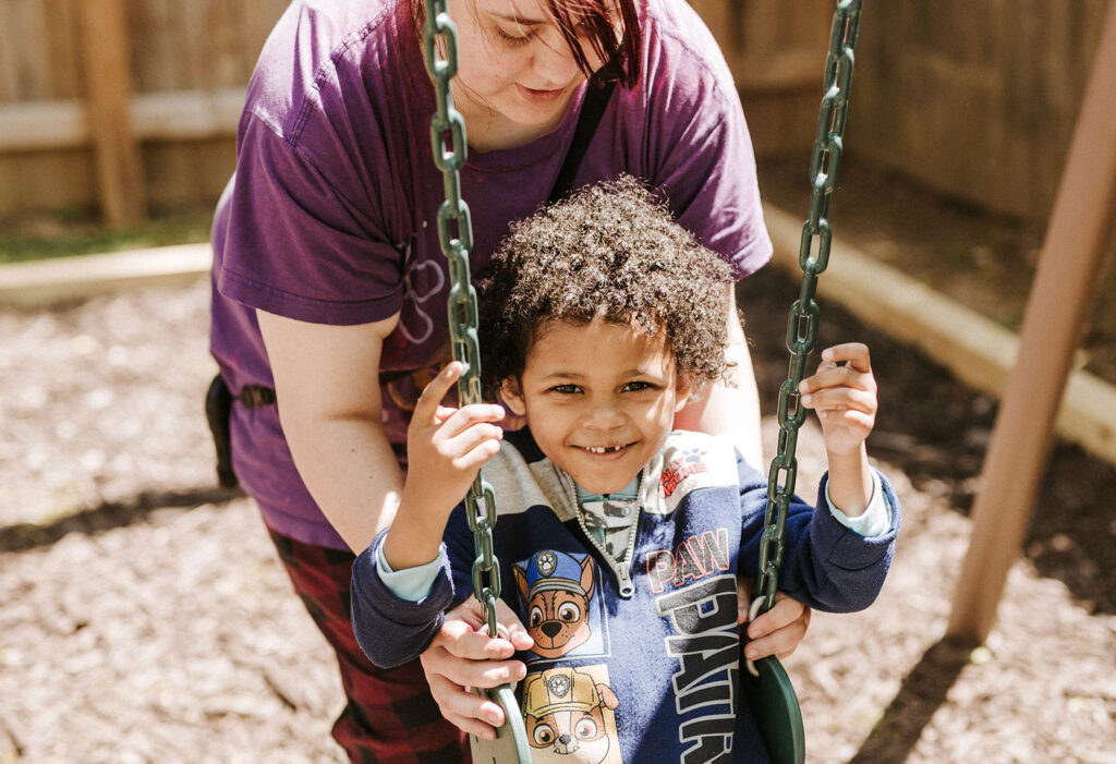 Caregiver with young child on swingset